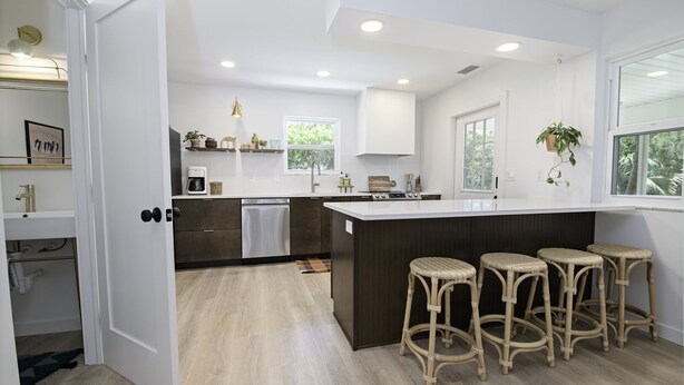 A modern kitchen with a central island, bar stools, and a view of the outdoors. - Pet friendly beach house w/private backyard & outdoor shower- steps from beach (St. Augustine)