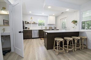 Una cocina moderna con una isla central, taburetes de bar y vistas al exterior.