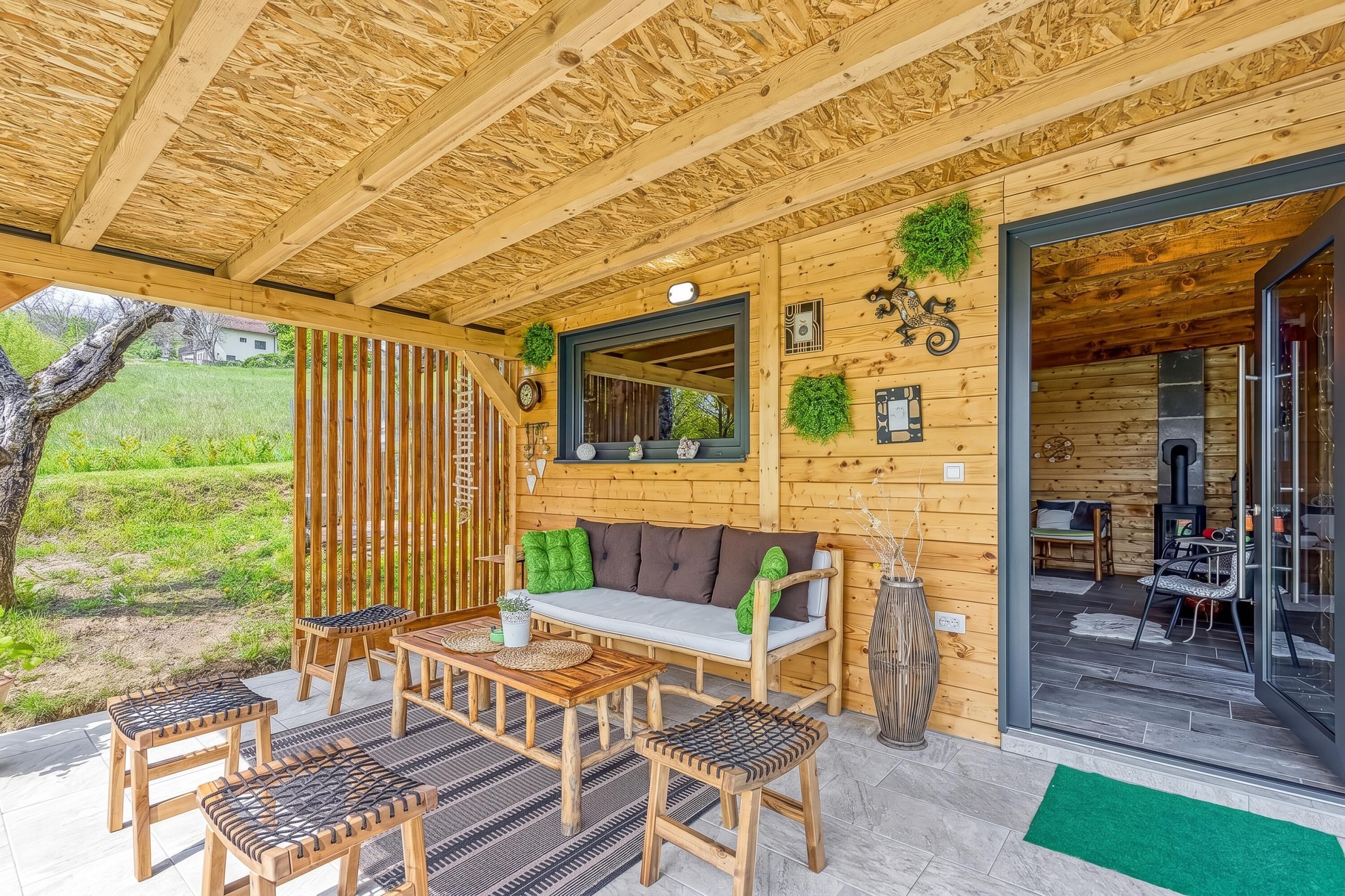 A wooden cabin with a covered patio, a sofa, a table, and chairs.