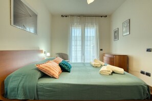 Une chambre à coucher avec un lit, une chaise, un bureau et une fenêtre avec des rideaux.