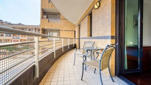 A balcony with a metal railing, two chairs, a small table, and a door leading to an interior room. - GuestHost - Cherenel House (Milan)