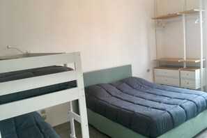 A bedroom with a bunk bed, a single bed, a wardrobe, and a nightstand.