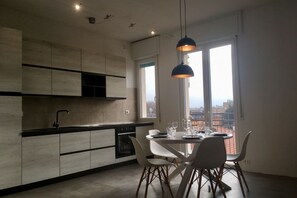 A modern kitchen with a dining area, large windows, and a city view.