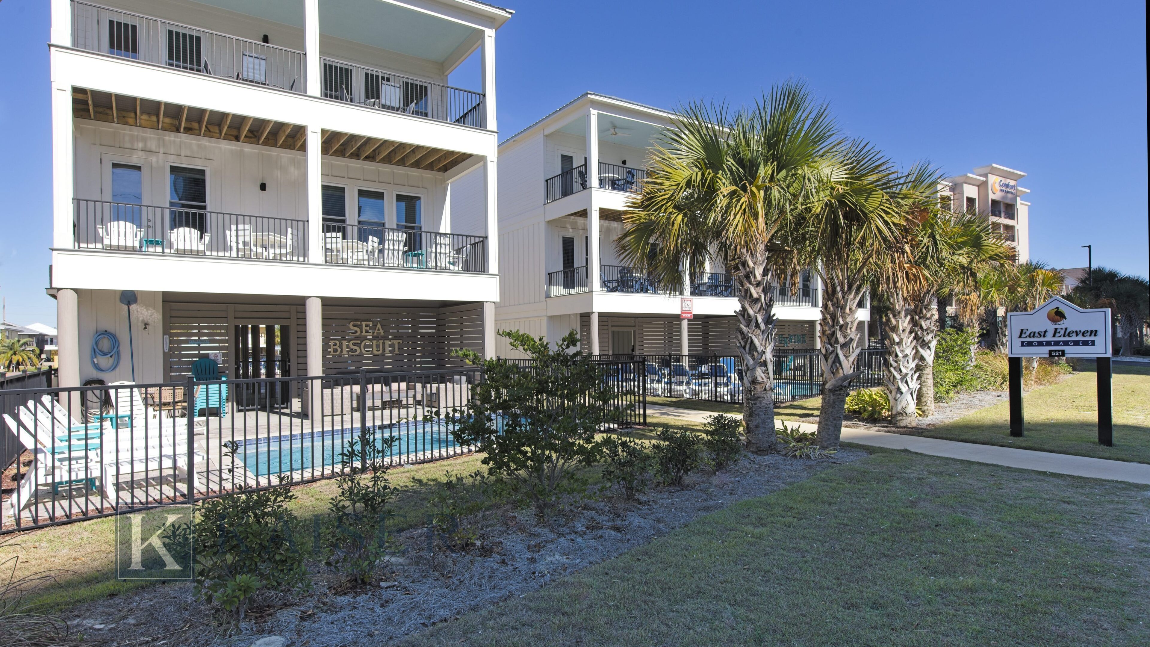 A multi-story hotel with a pool area, palm trees, and a sign for 'East Eleven Cottages'.