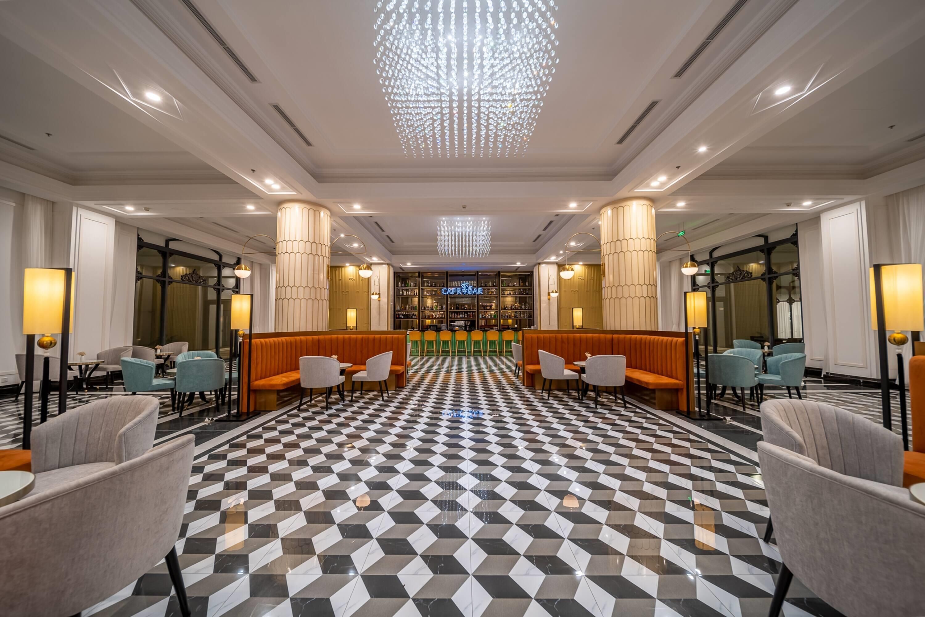 Un vestíbulo de hotel con piso a cuadros, zonas de estar y un bar central.