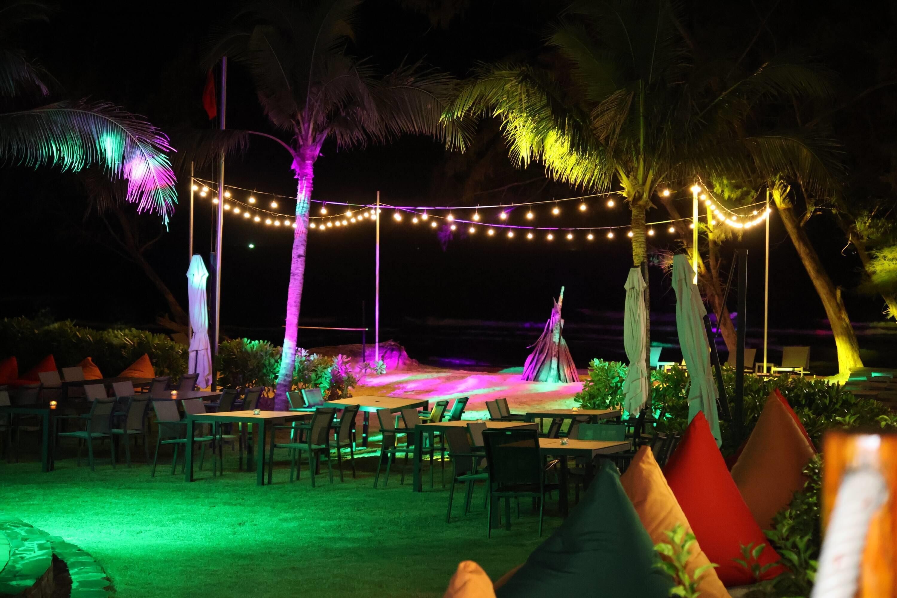 An outdoor dining area with tables and chairs, string lights, and a tent.