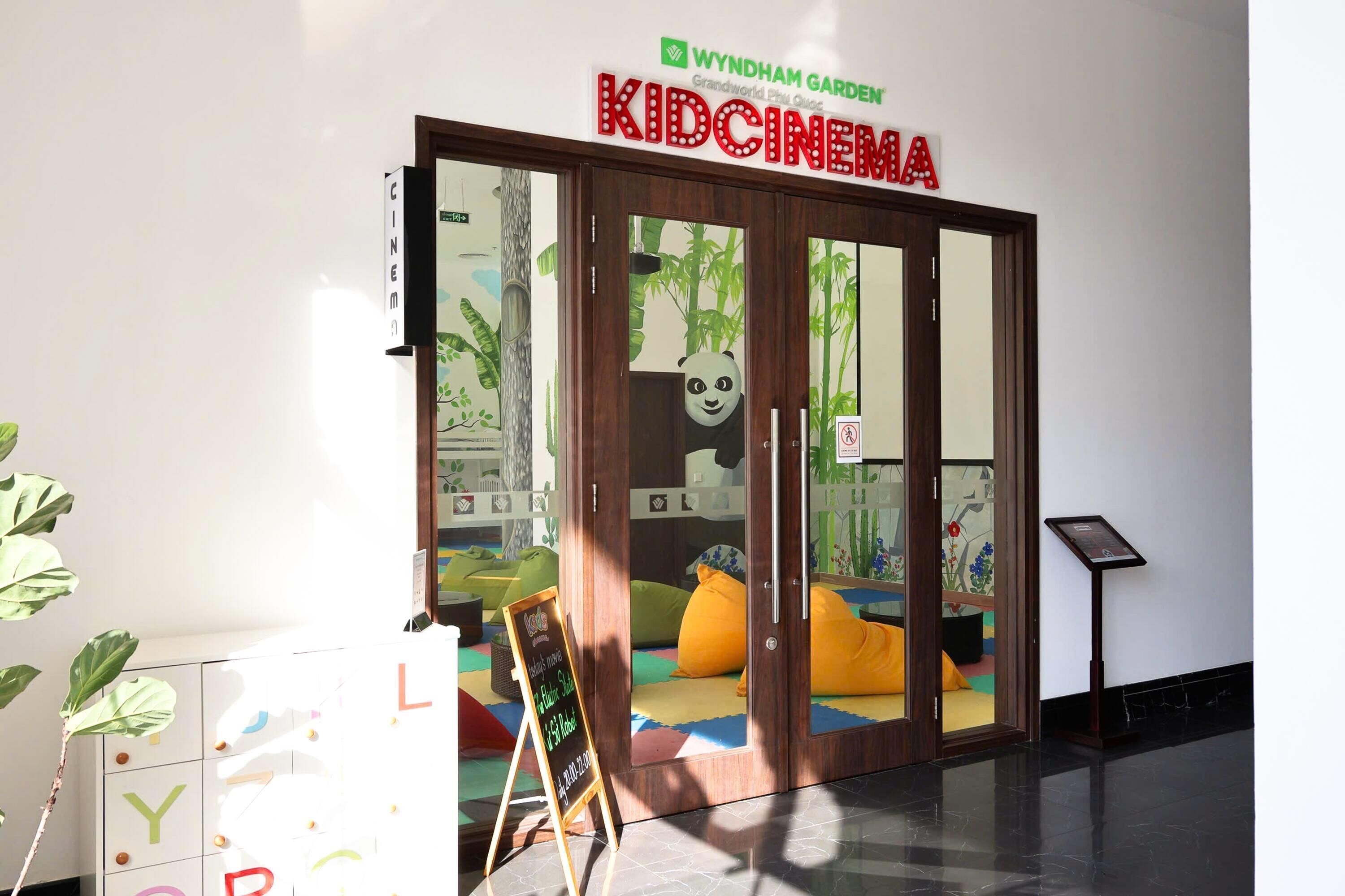 A KidCinemat entrance with a panda cutout, a signboard, and colorful cushions.