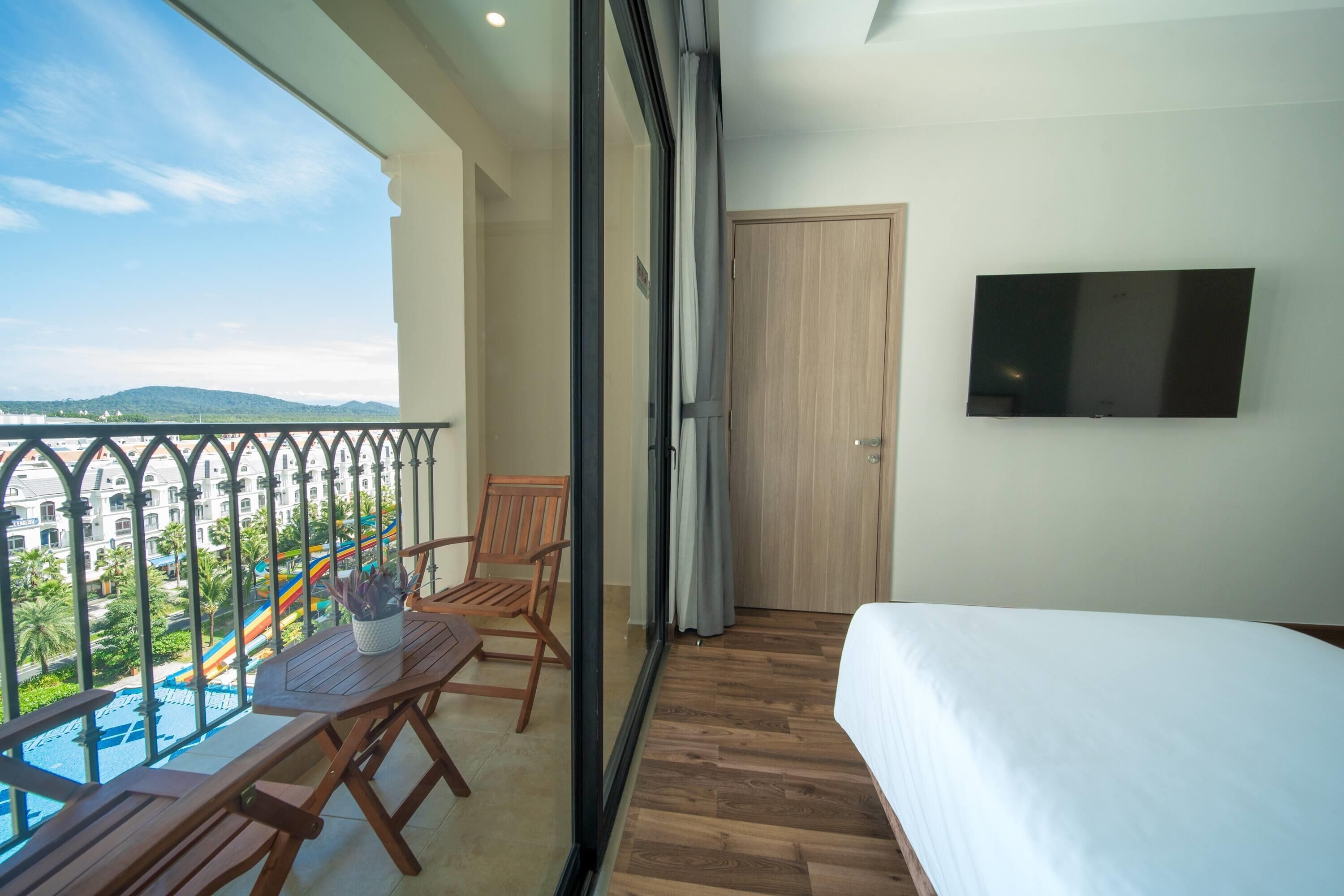 A balcony with a wooden table, chairs, and a TV mounted on the wall.