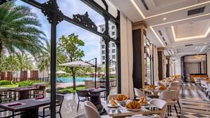 A hotel dining area with tables set for guests, a pool view, and a modern interior design.