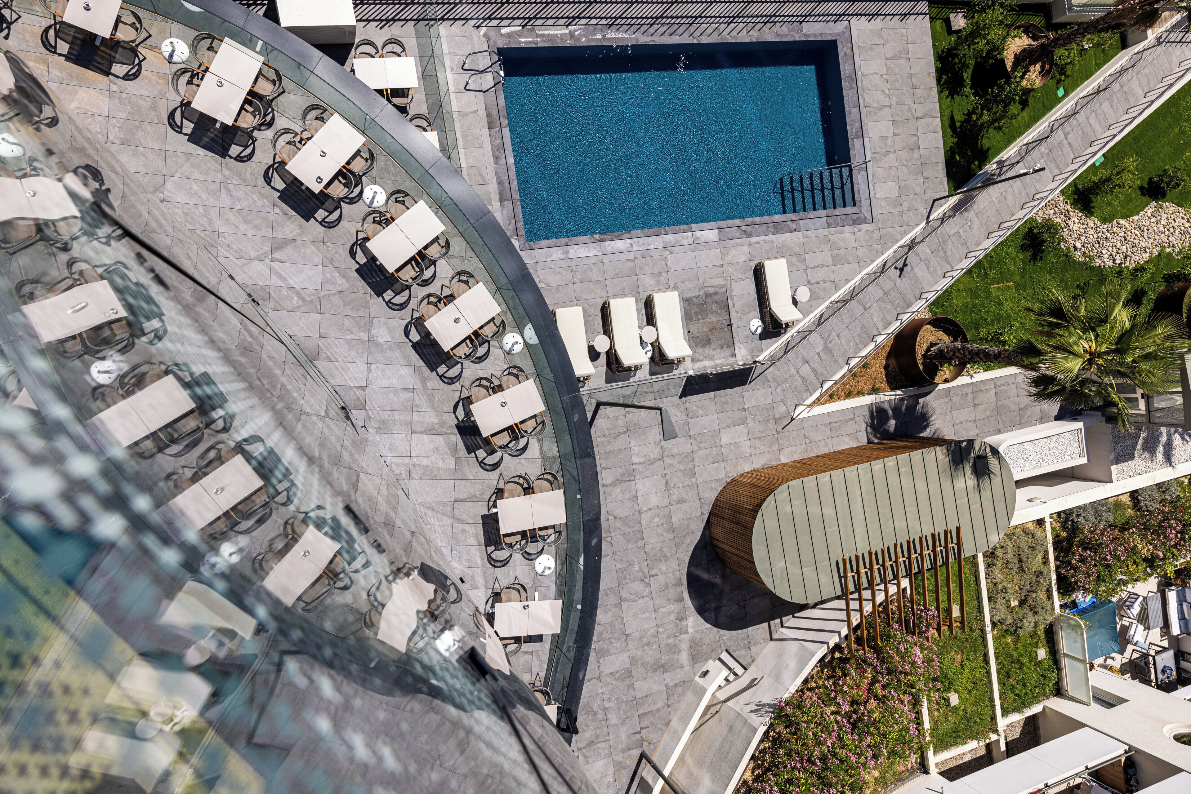 Vista aérea de un área de piscina en la azotea, con sillones de descanso y una piscina.