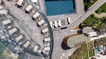 Vista aérea de un área de piscina en la azotea, con sillones de descanso y una piscina.