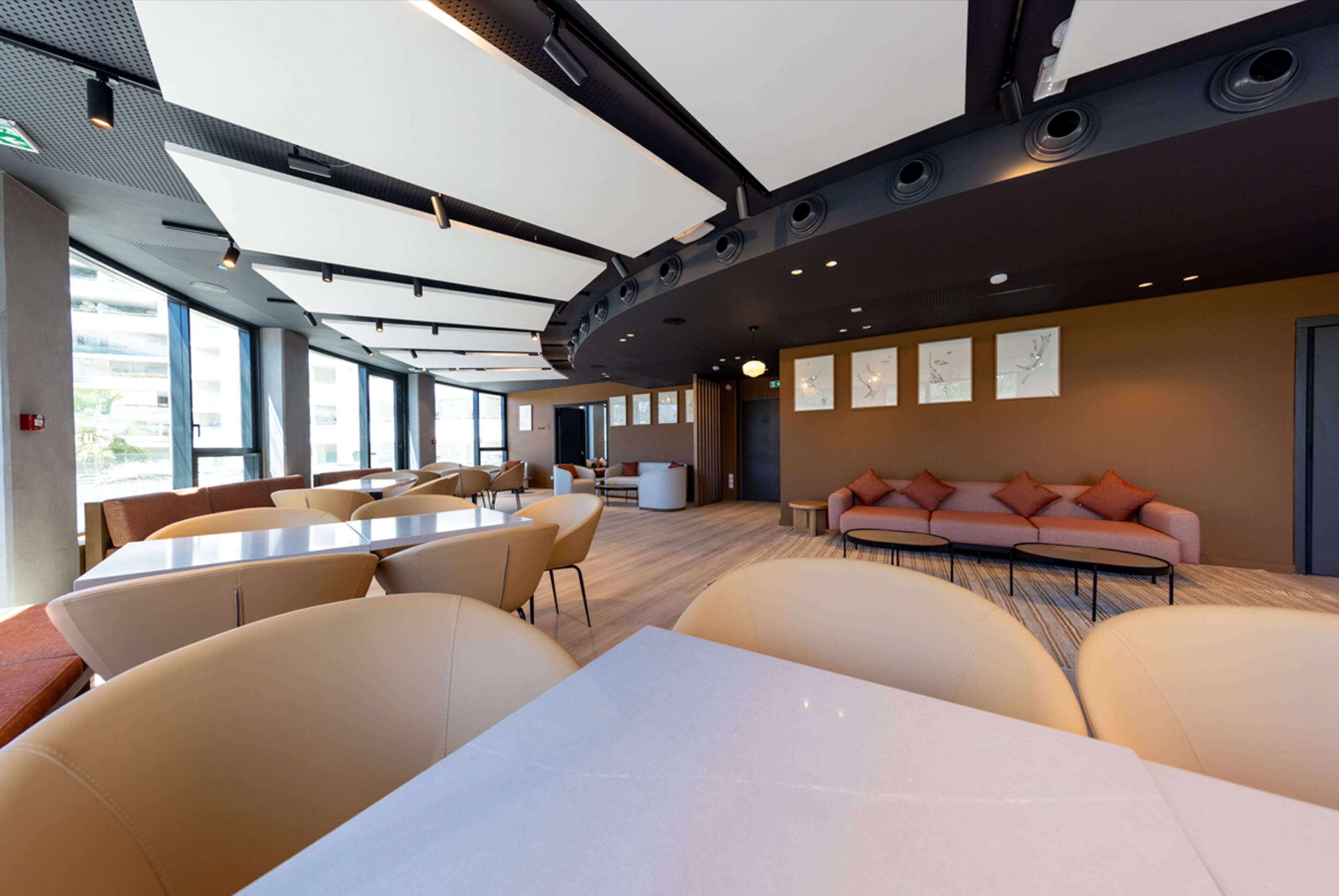 A modern conference room with tables and chairs, a sofa, and artwork on the walls.