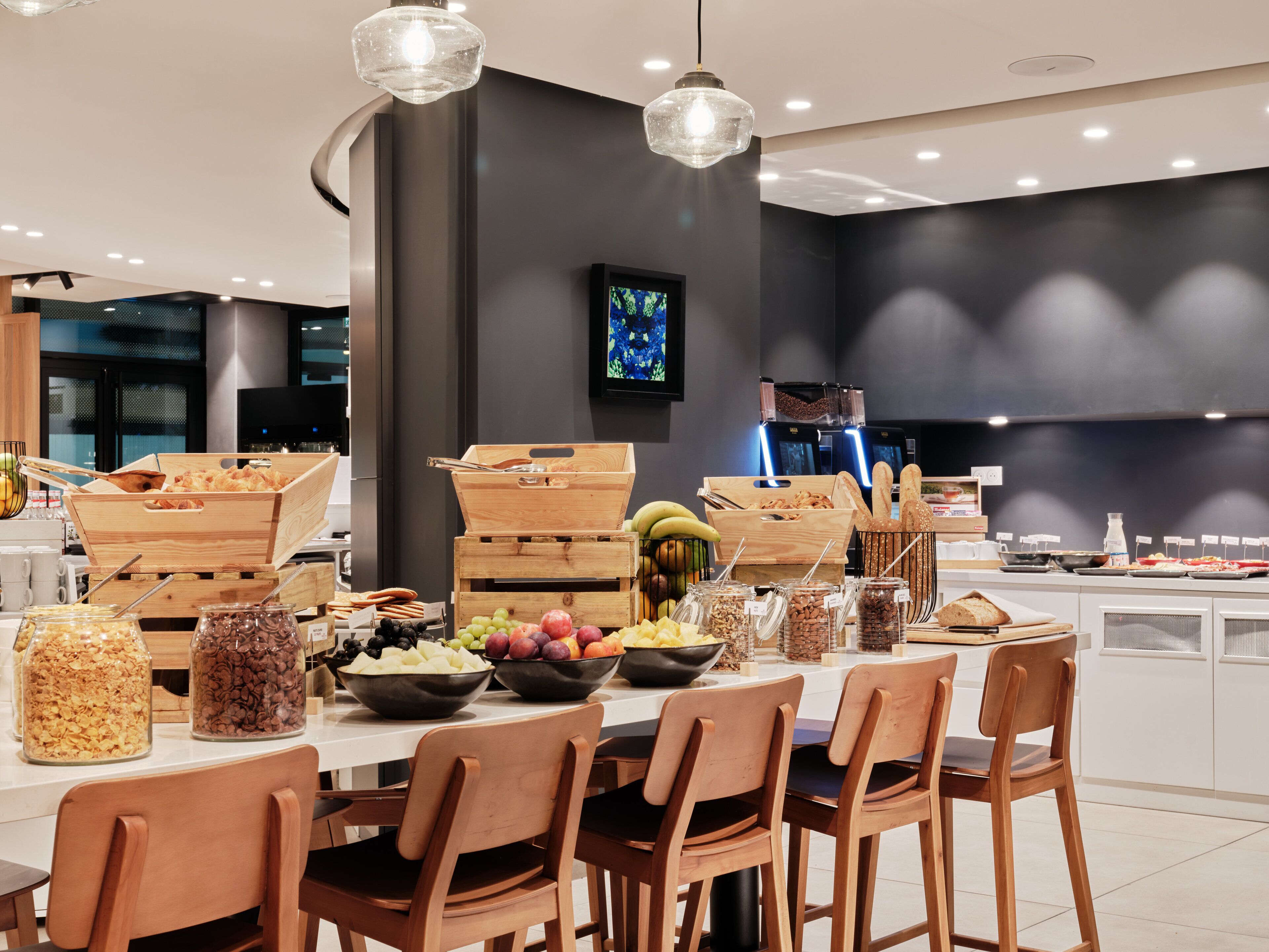 Un comedor moderno con sillas de madera, una mesa blanca y diferentes alimentos exhibidos sobre la mesa.