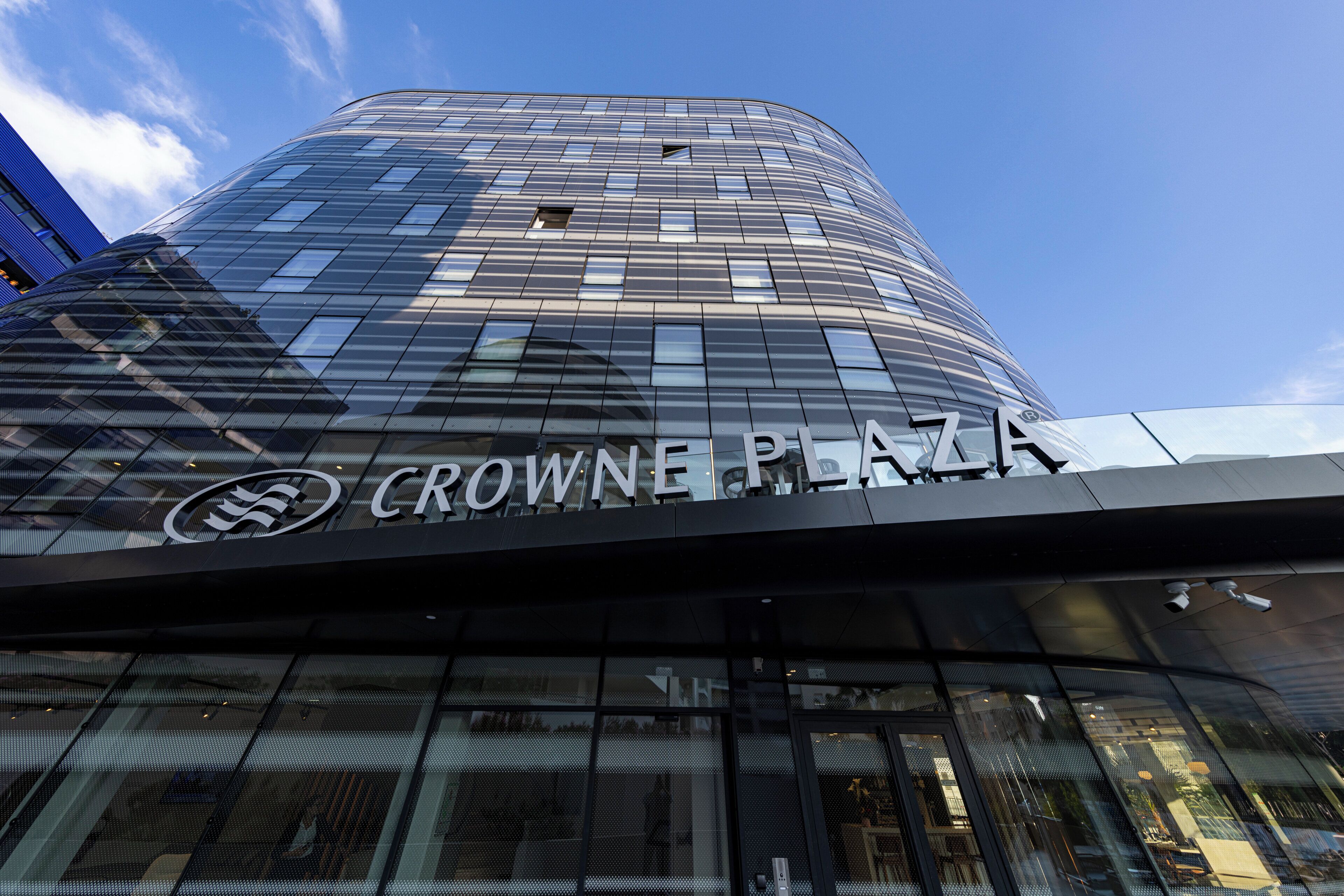 Un bâtiment moderne portant l’enseigne « CROWNE PLAZA », ce qui indique qu’il s’agit d’un espace commercial.