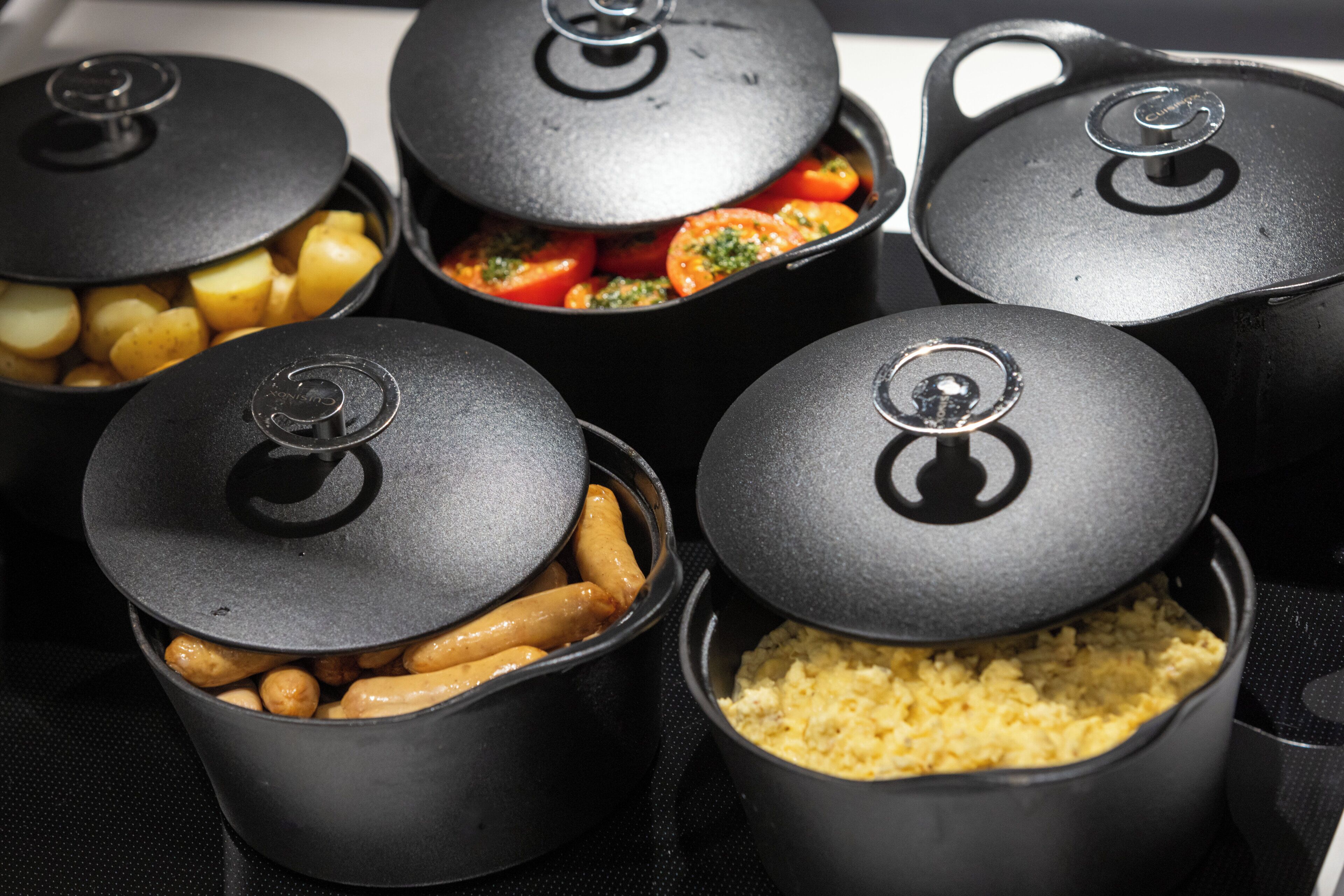 A set of black containers with lids, each containing different food items.
