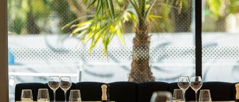 Une table de restaurant avec des verres à vin et des couverts vides, un pion d’échecs et une plante en pot en arrière-plan.