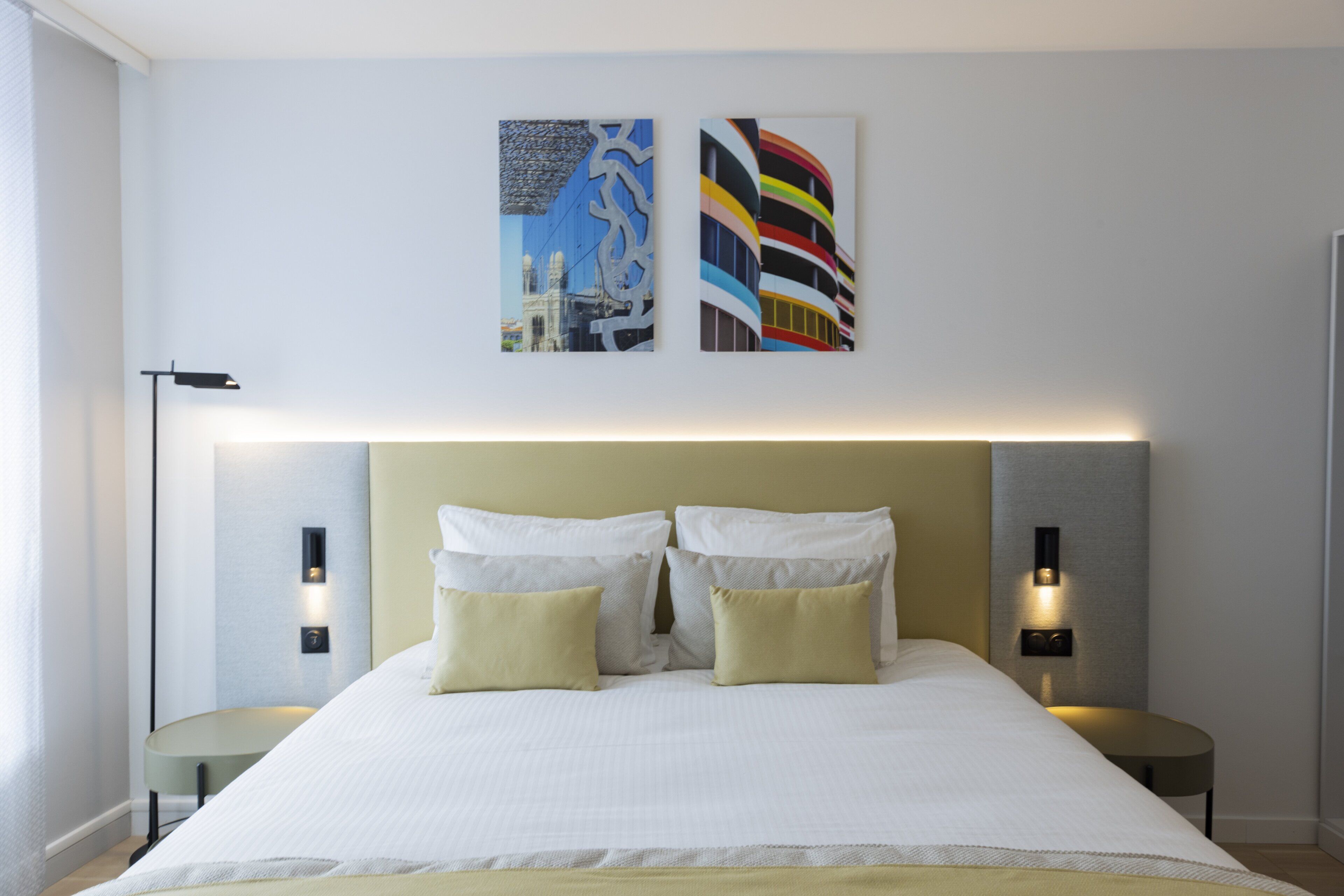 Una habitación de hotel moderna con una cama grande, dos mesitas de noche e iluminación empotrada en la pared.