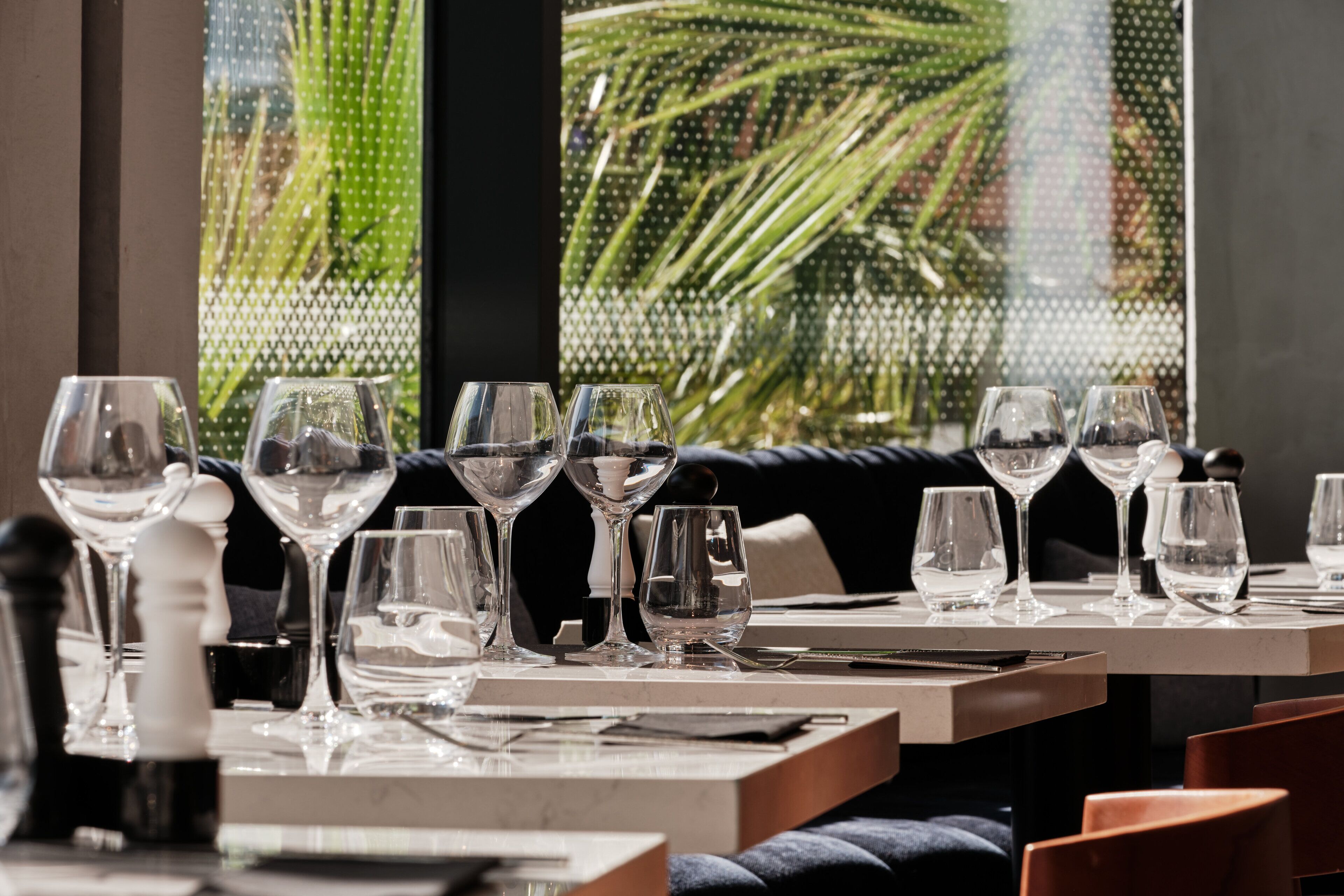 Un ambiente de restaurante con mesas dispuestas para comer, con cristalería y cubertería elegantes.