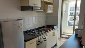 Cocina moderna con refrigerador, estufa, horno y microondas. Una ventana ofrece vistas al exterior.