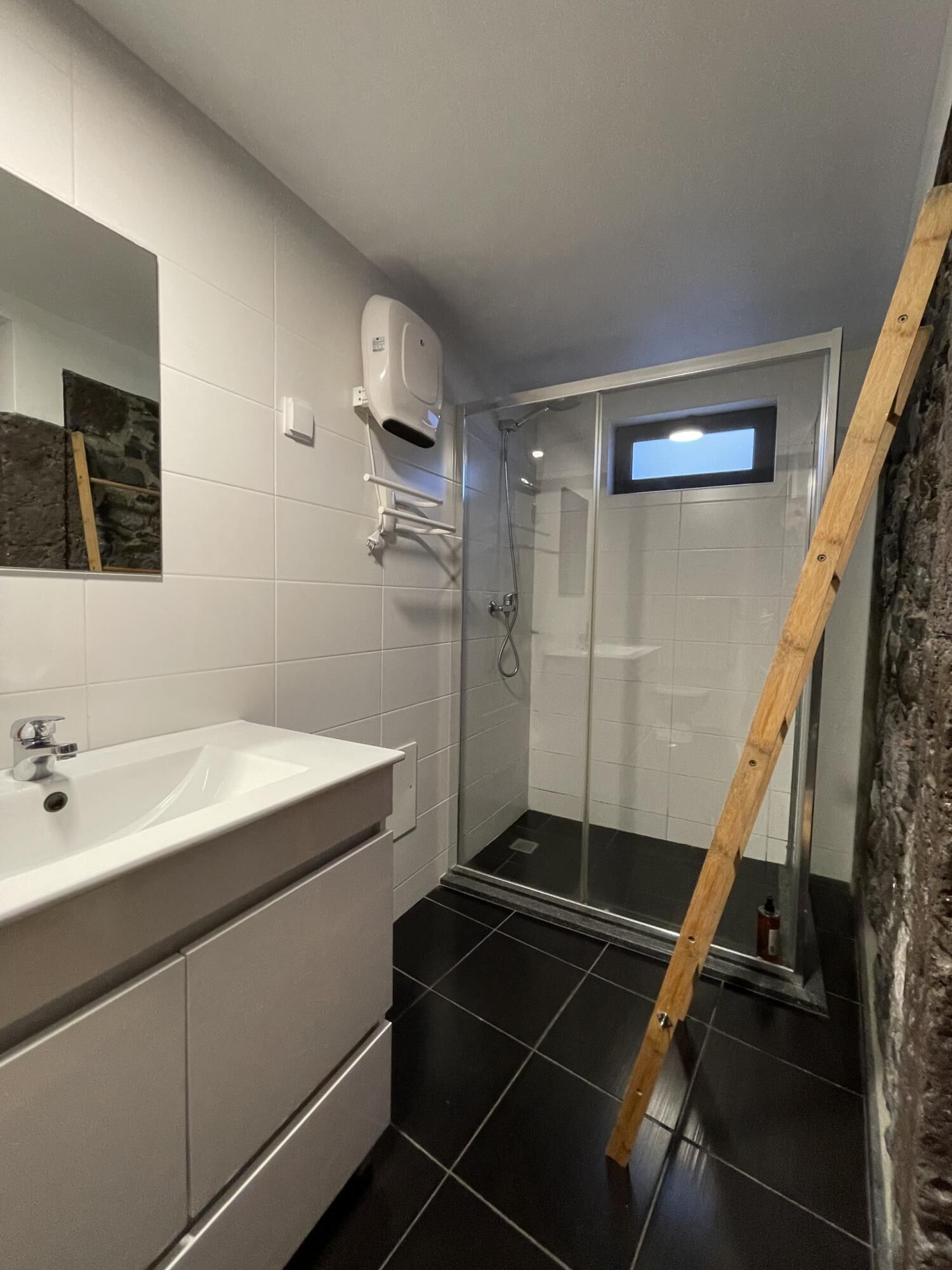 Un baño moderno con lavamanos blanco, espejo y zona de ducha.