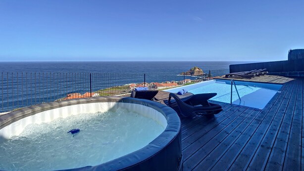 A hot tub and a pool on a wooden deck with a view of the ocean. - Villa das Escaleiras (Porto Moniz)