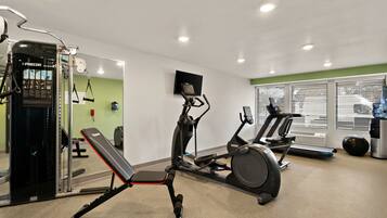 A gym with exercise equipment, a bench, and a treadmill.