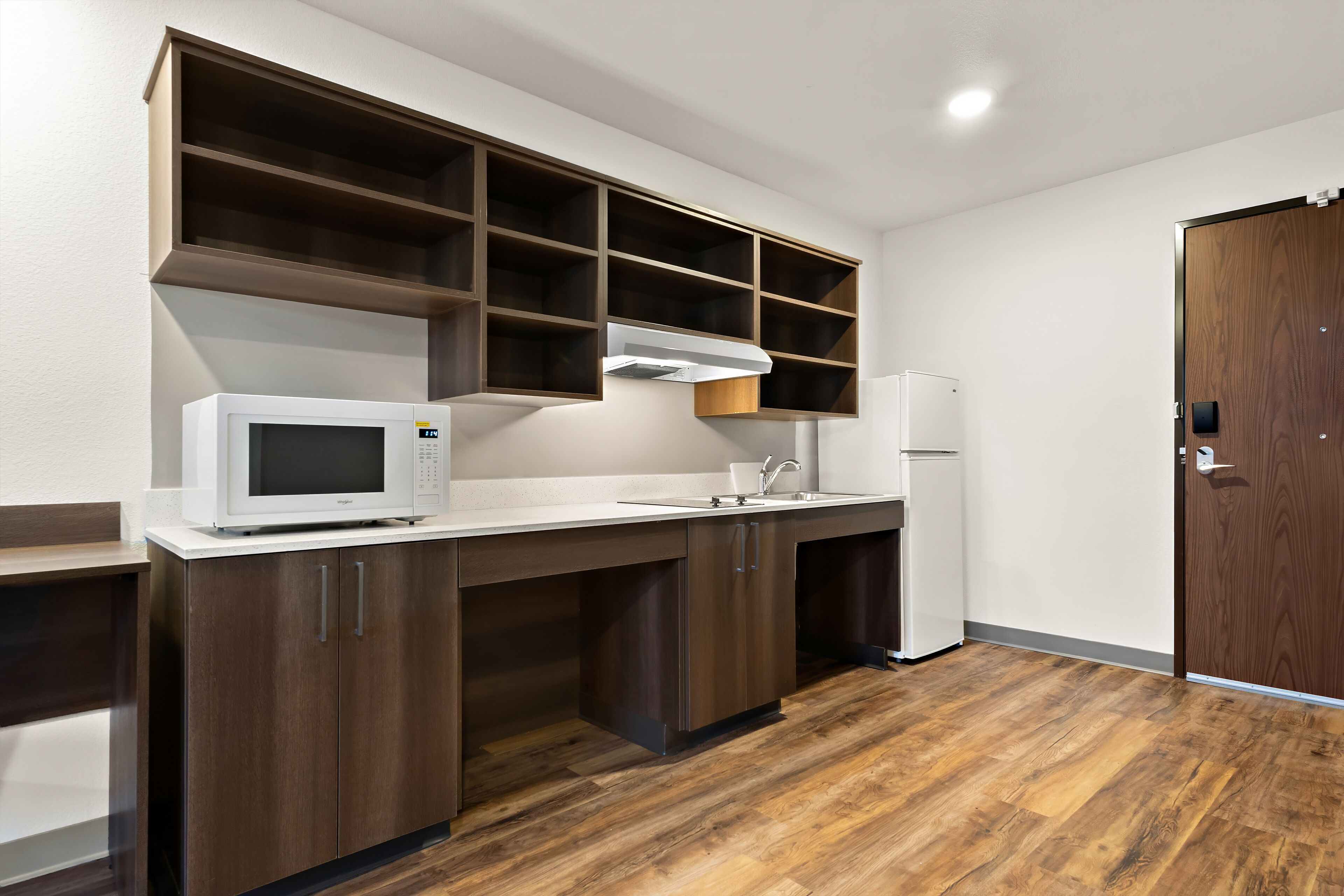 Una cocina moderna con armarios integrados, microondas y refrigerador.