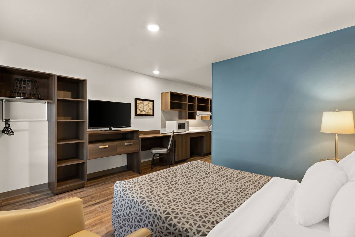 A hotel room with a bed, a desk, a television, a microwave, and a wardrobe.