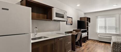A compact kitchen with a refrigerator, microwave, and wooden cabinets.