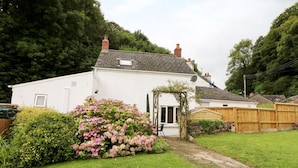 A white house with a sloped roof, a brick chimney, and a small window. - Spring Garden Cottage (Carmarthen)