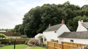 A residential area with white houses, a wooden fence, and a large tree in the background. - Spring Garden Cottage (Carmarthen)