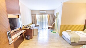Una habitación de hotel con televisión, sofá, cama, escritorio y una silla.