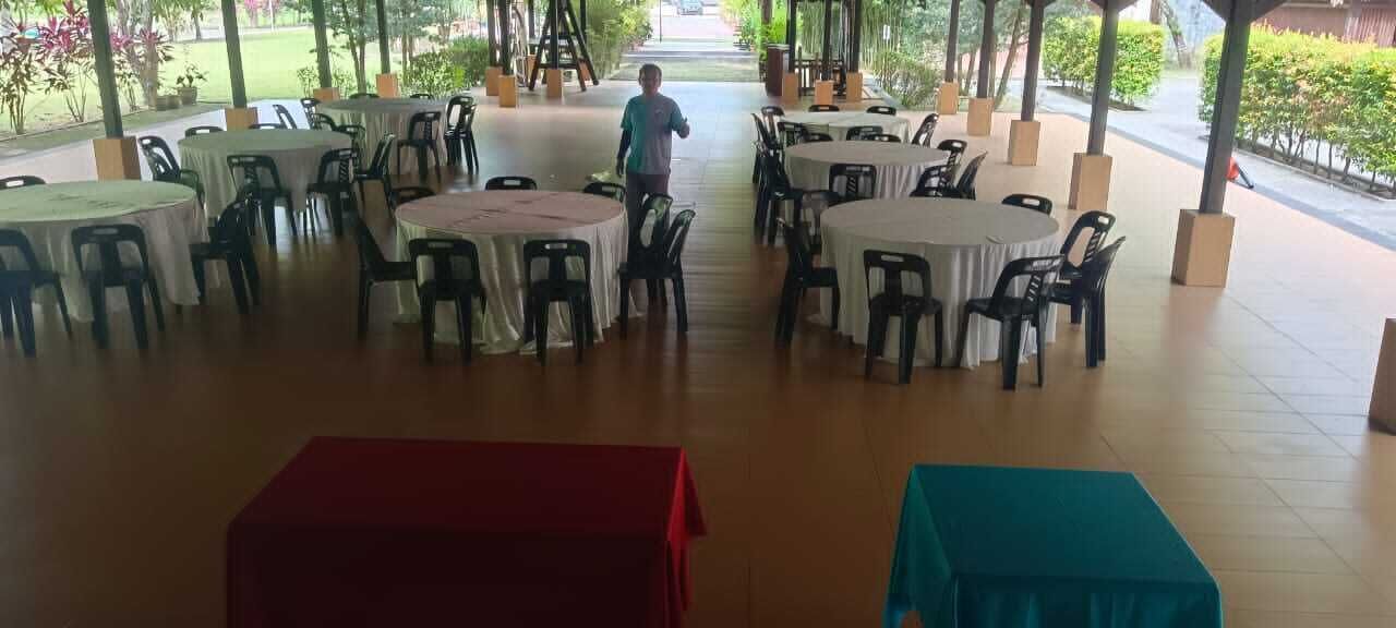 An outdoor dining area with round tables and chairs, a person walking, and a covered walkway.