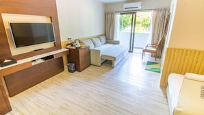 Habitación de hotel con televisión de pantalla plana, cama, sofá, sillón y una pequeña mesa.