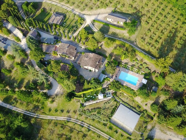 An aerial view of a residential area with multiple houses, a swimming pool, and a large open field.