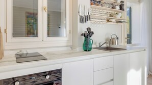 A kitchen with white cabinets, a marble countertop, a built-in oven, a sink, and a window with blinds. - Porto Letizia Orchidea 6, Porlezza, Italy (Porlezza)