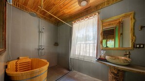 A bathroom with a wooden bathtub, a shower, a vanity with a stone sink, and a mirror with a wooden frame. - Puluong Luna Resort (Pu Luong)