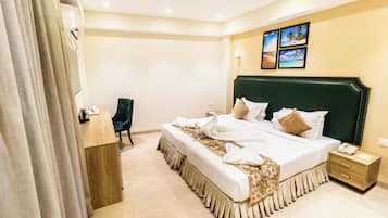 Ein Hotelzimmer mit einem großen Bett, einem Schreibtisch, einem Sessel und einem Nachttisch.