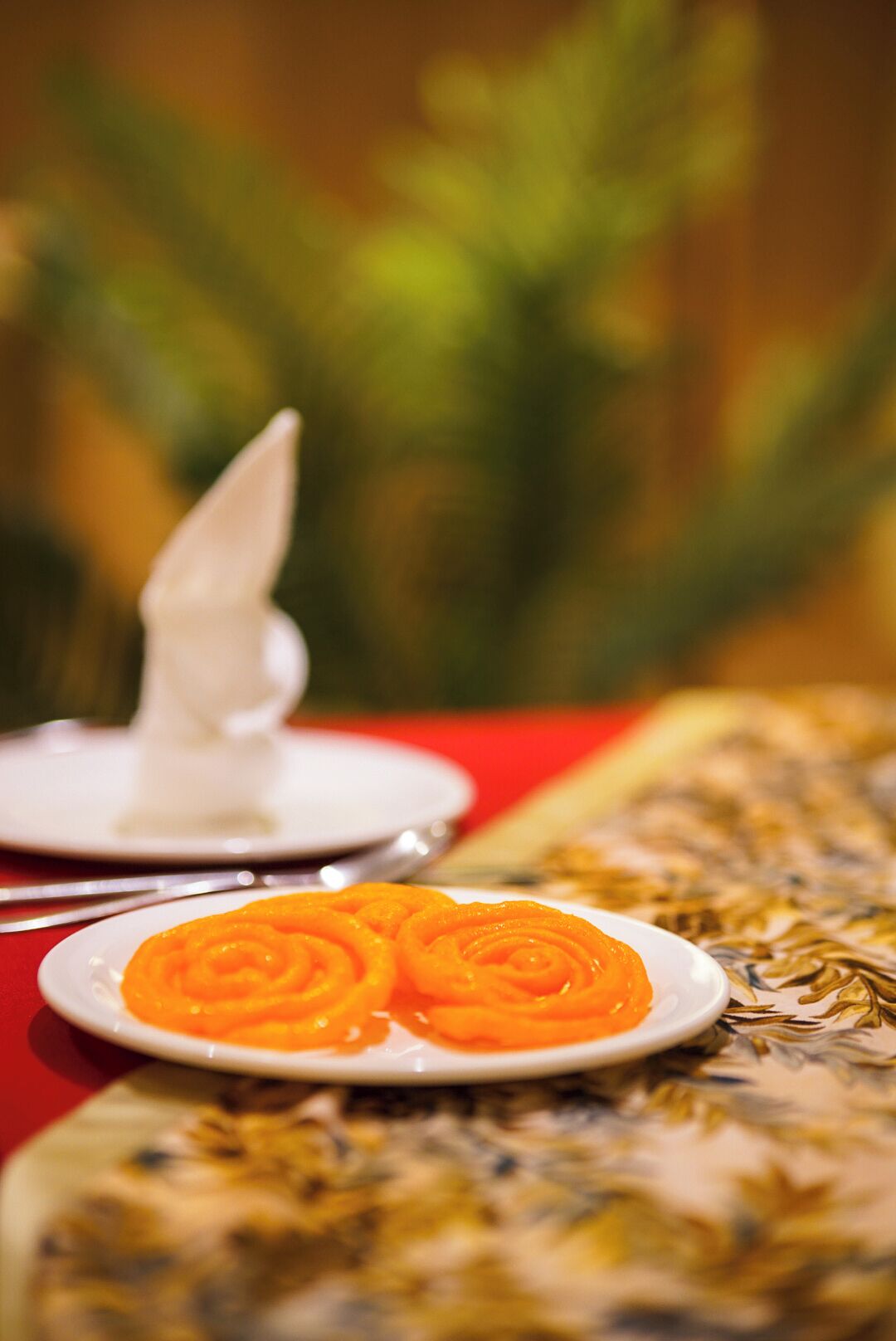 A plate of orange dessert on a table with a red tablecloth.