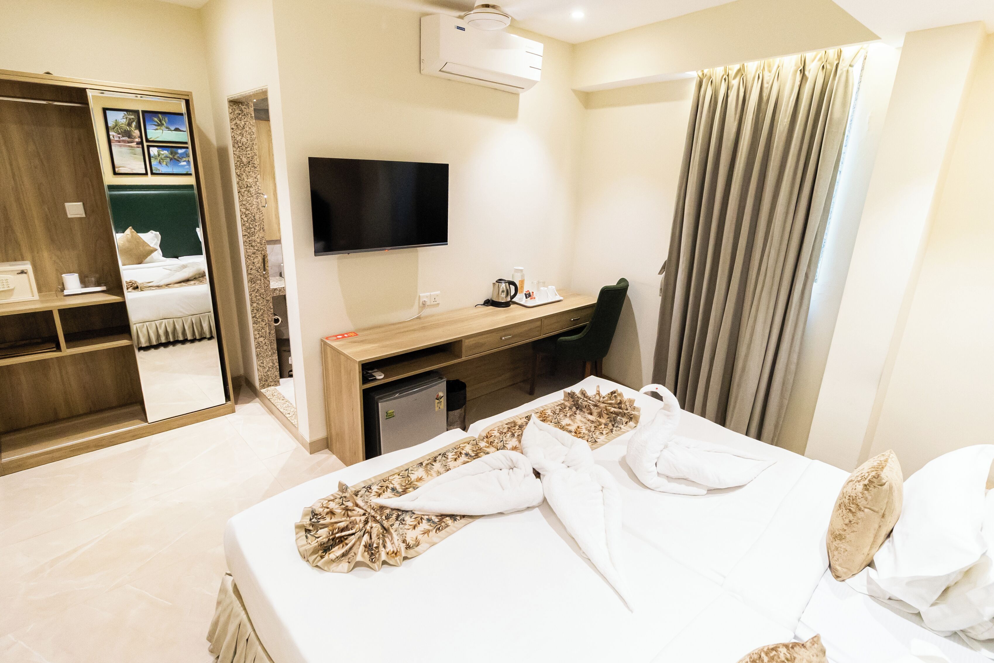 Una habitación de hotel con cama, escritorio, silla, televisor y armario.