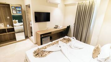 Una habitación de hotel con cama, escritorio, silla, televisor y armario.