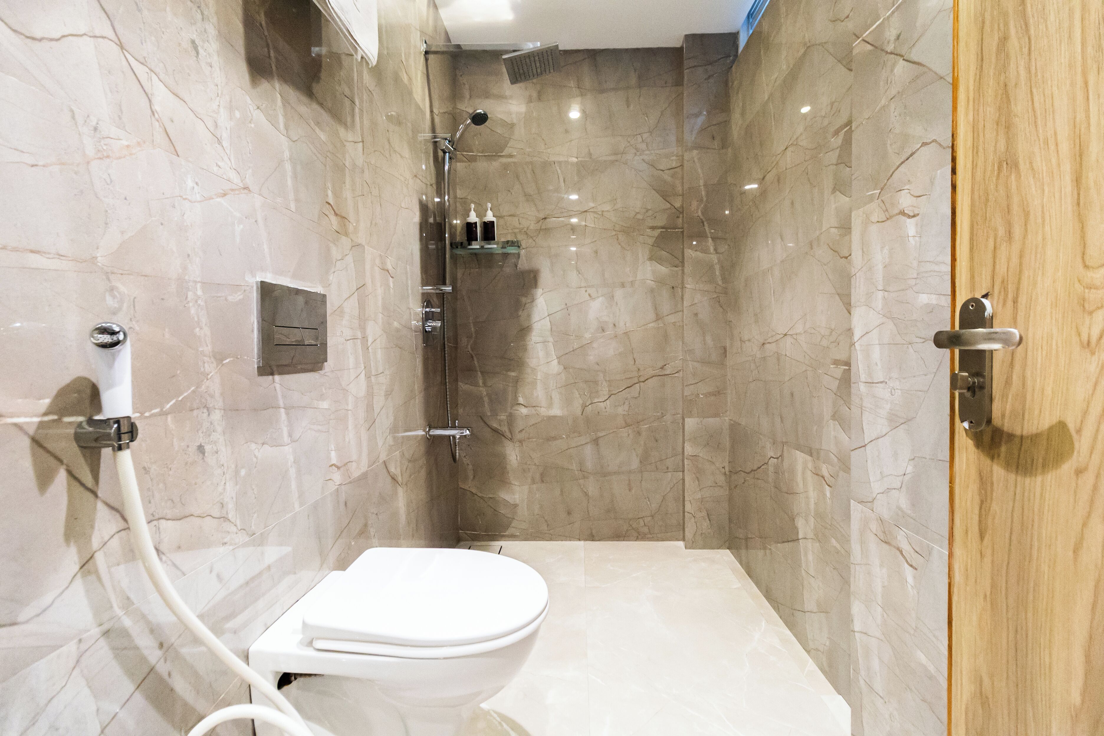Un baño moderno con ducha, inodoro y paredes de mármol.