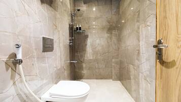 Un baño moderno con ducha, inodoro y paredes de mármol.
