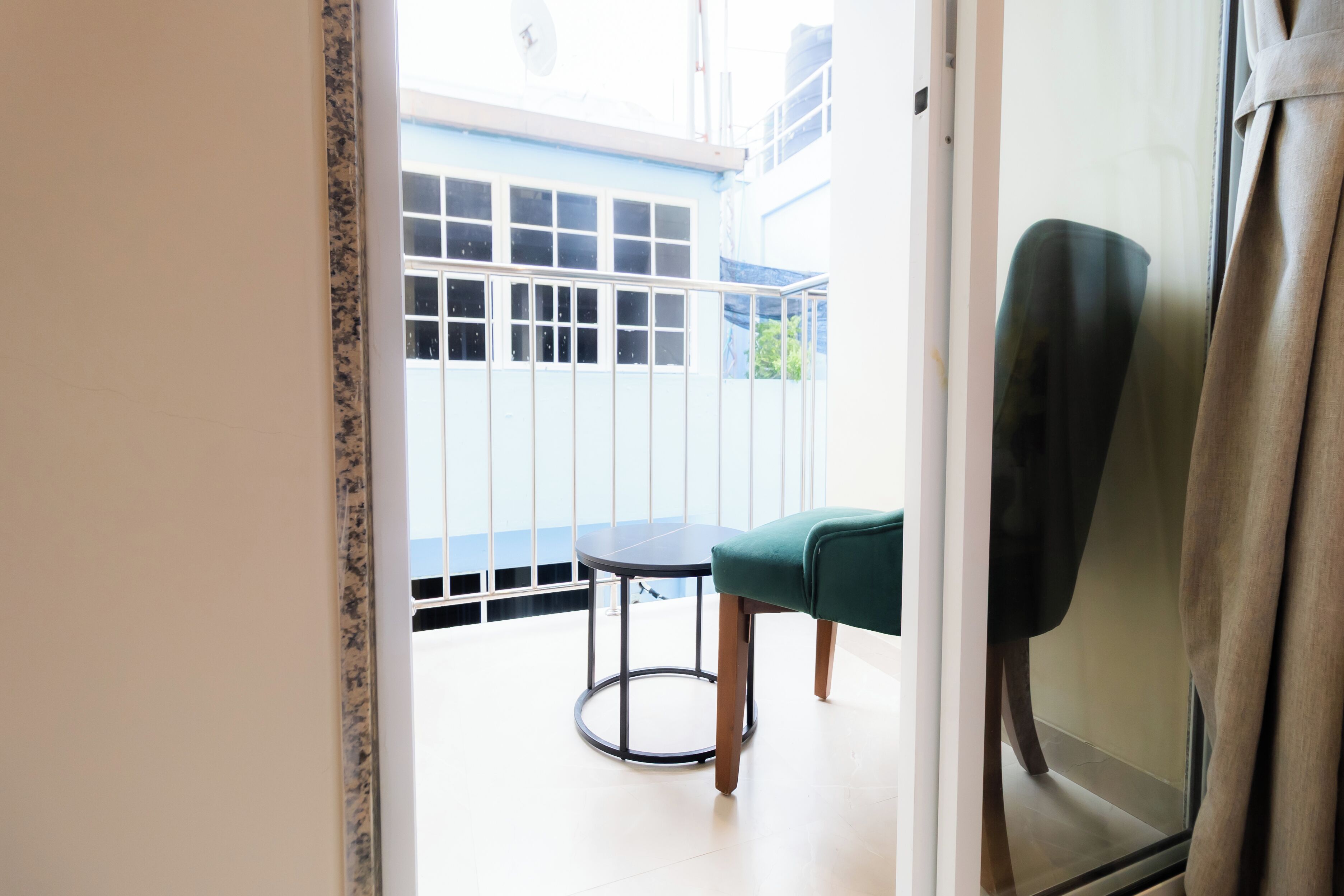 A room with a view of a blue building, a round table, and a green chair.