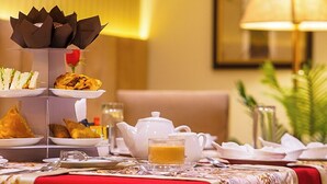 Une table à manger dressée avec une variété de plats, une théière et une lampe.