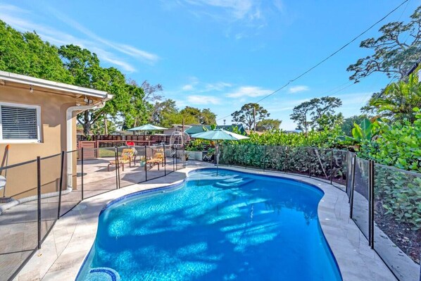 Relax by the oval-shaped pool surrounded by lounge chairs and lush greenery.