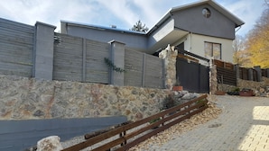 Um edifício moderno com parede de pedra, cerca de madeira e área pavimentada com folhas espalhadas.