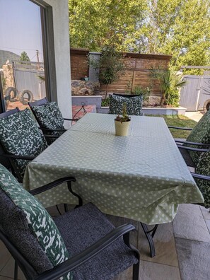 An outdoor patio with a table covered in a green polka dot tablecloth, surrounded by chairs with patterned cushions. - Turkish Mountain Retreat (Saadet)