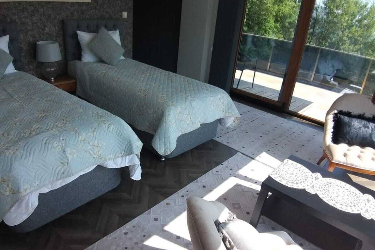 A bedroom with two beds, a sofa, and a large window.