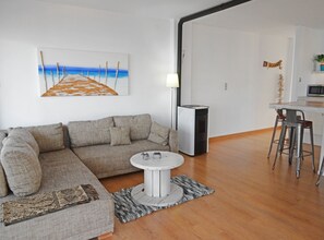 A modern living room with a sectional sofa, a round coffee table, and a painting of a beach scene. - Garza Playa - Altea, Costa Blanca (Altea)
